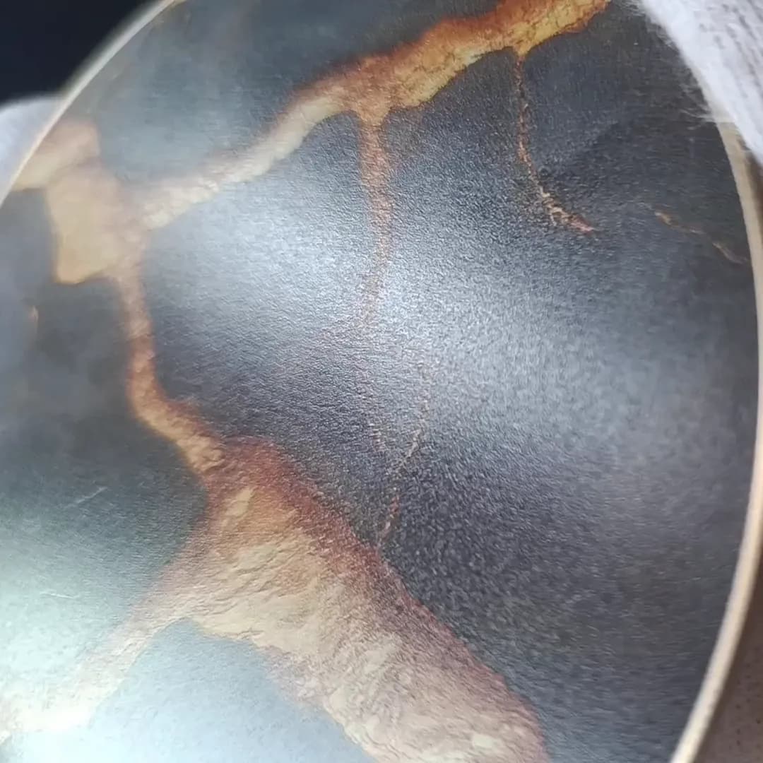Black Marble & Gold coaster held close in white cotton gloves, light moving across the printed front