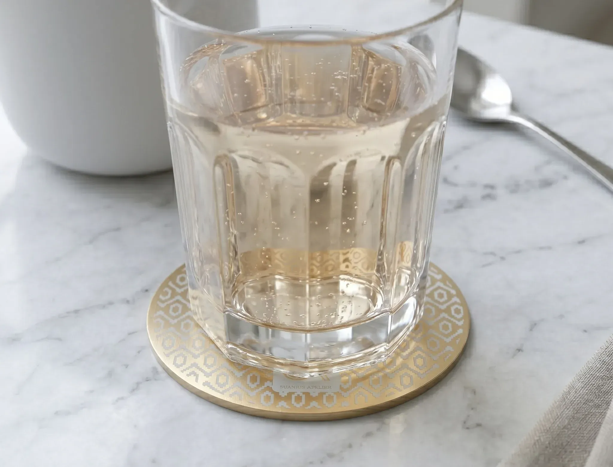 topographic PCB coaster styled on a desk beside a cup