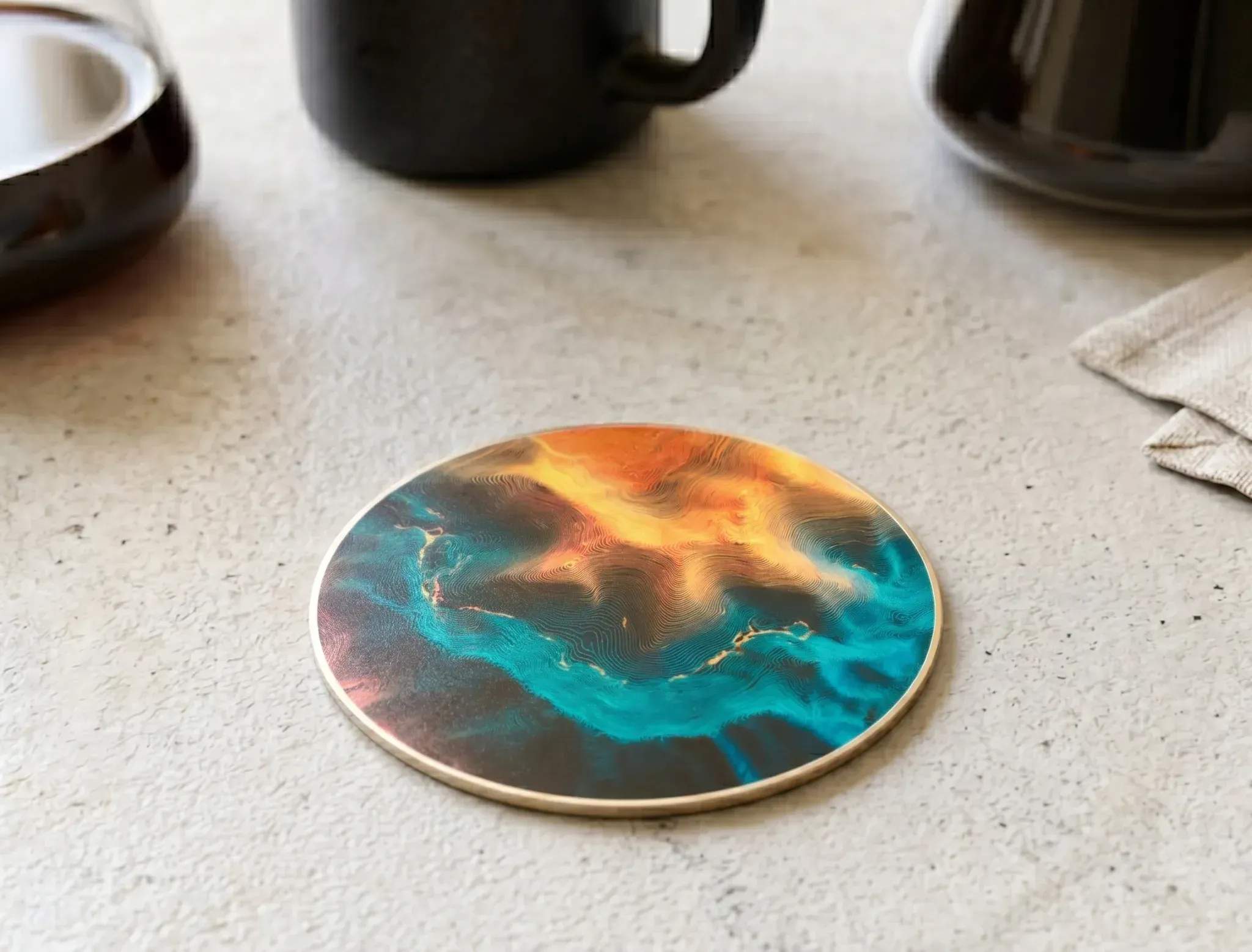 topographic PCB coaster styled on a desk beside a cup